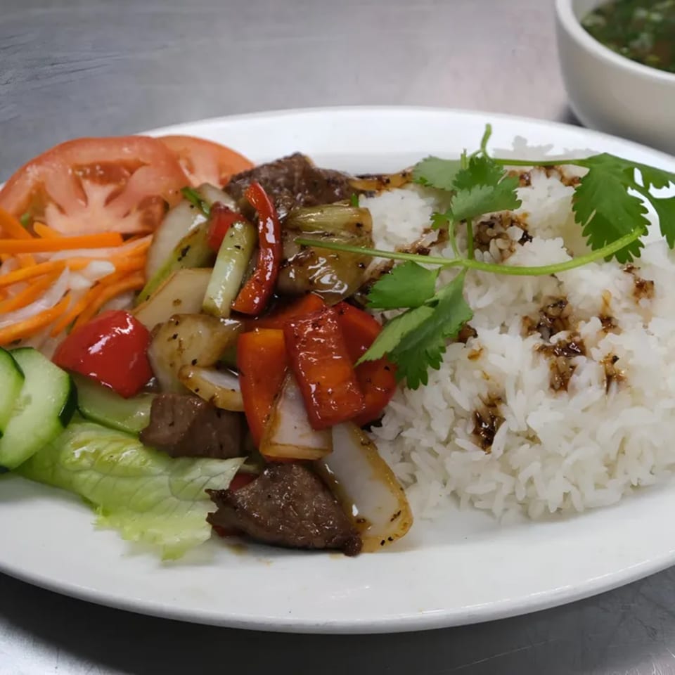 Vietnamese shaking beef (Bo Luc Lac) with white rice, fresh vegetables, and a side of soup.